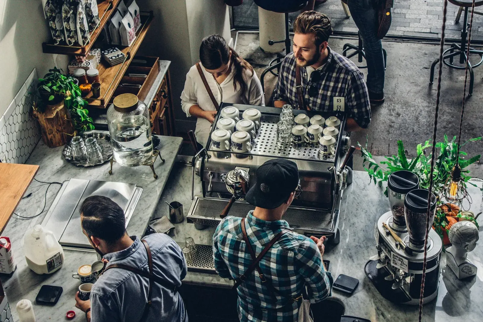 Busy independent coffee shop with baristas working behind the counter and customers waiting