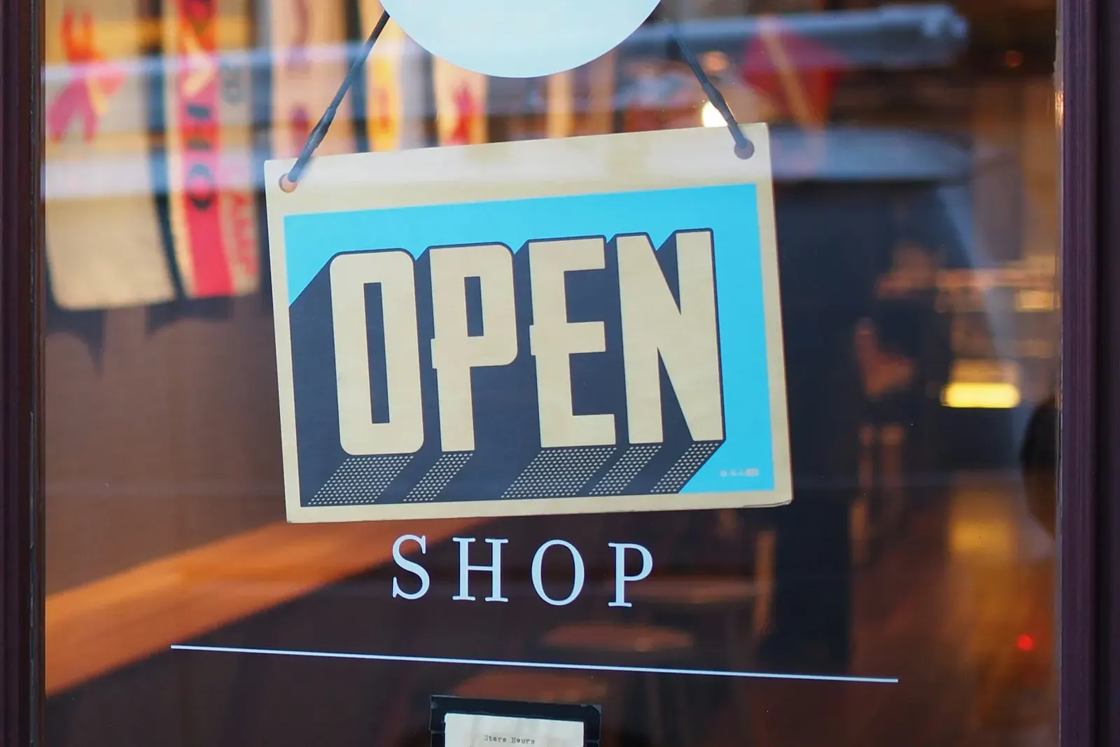 Open sign hanging in the glass door of a small shop