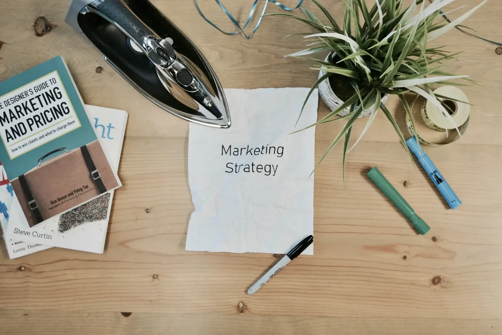 Desk with marketing books, a notebook and a sheet of paper titled marketing strategy